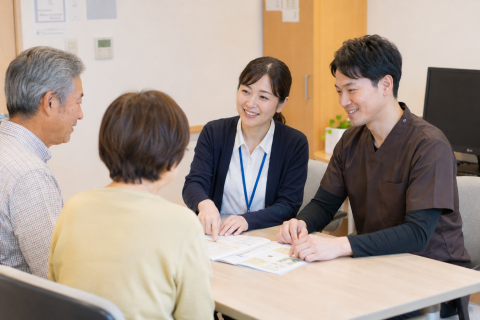 京都市の回復期病院で地域連携室の相談員と家族、理学療法士が退院後のリハビリについて相談している様子
