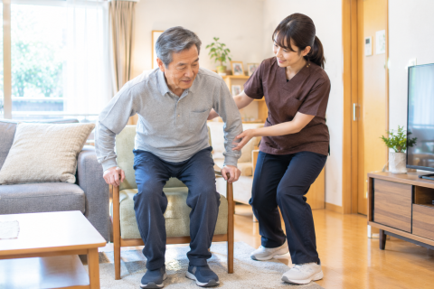 脳梗塞の退院後に自宅で理学療法士と立ち上がり練習を行う男性