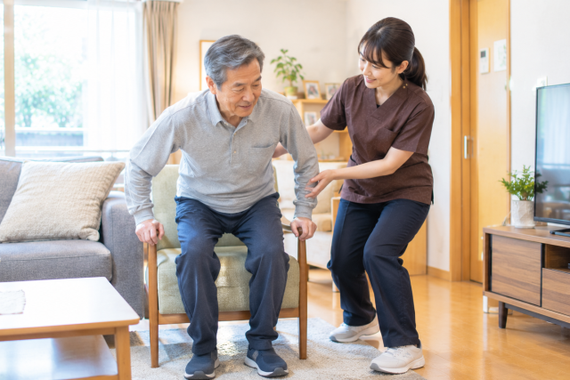 脳梗塞の退院後に自宅で理学療法士と立ち上がり練習を行う男性