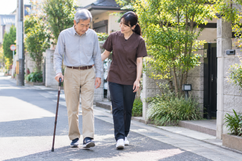 脳卒中後の男性が理学療法士と屋外で歩行訓練を行っている様子