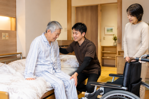 京都市下京区で理学療法士が寝たきりの利用者へ訪問リハビリを行い、ベッドから車椅子への移乗をサポートしている様子